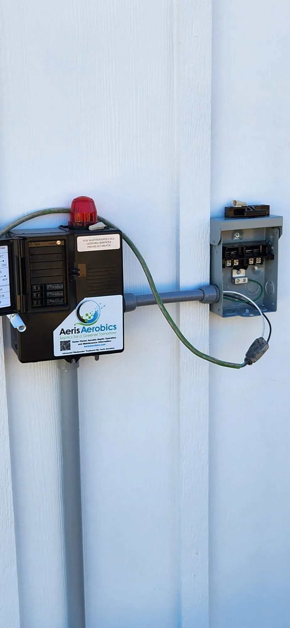 An Aeris Aerobics control panel and alarm mounted on the side of a home