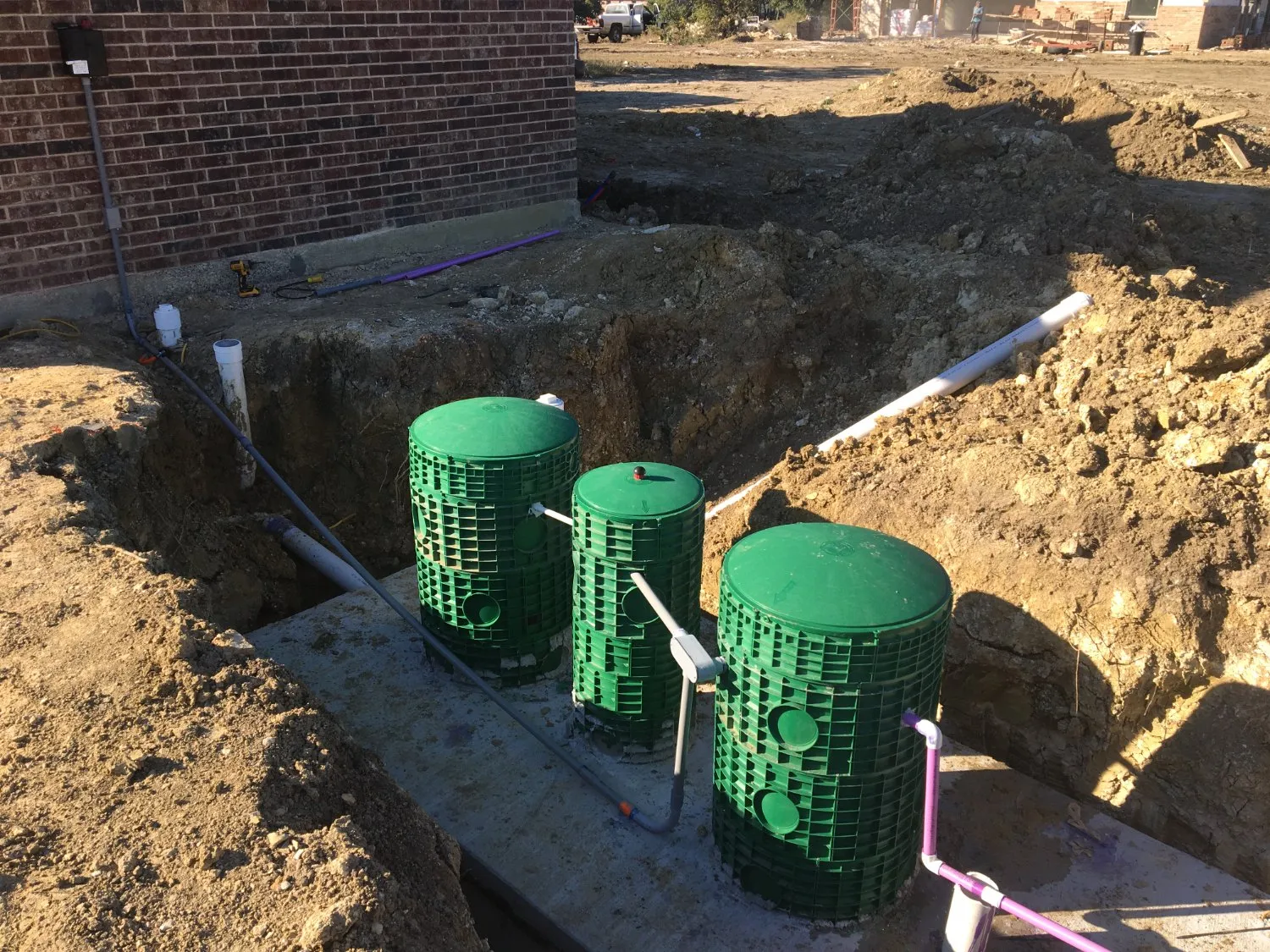Aerobic septic risers being installed beside a brick home