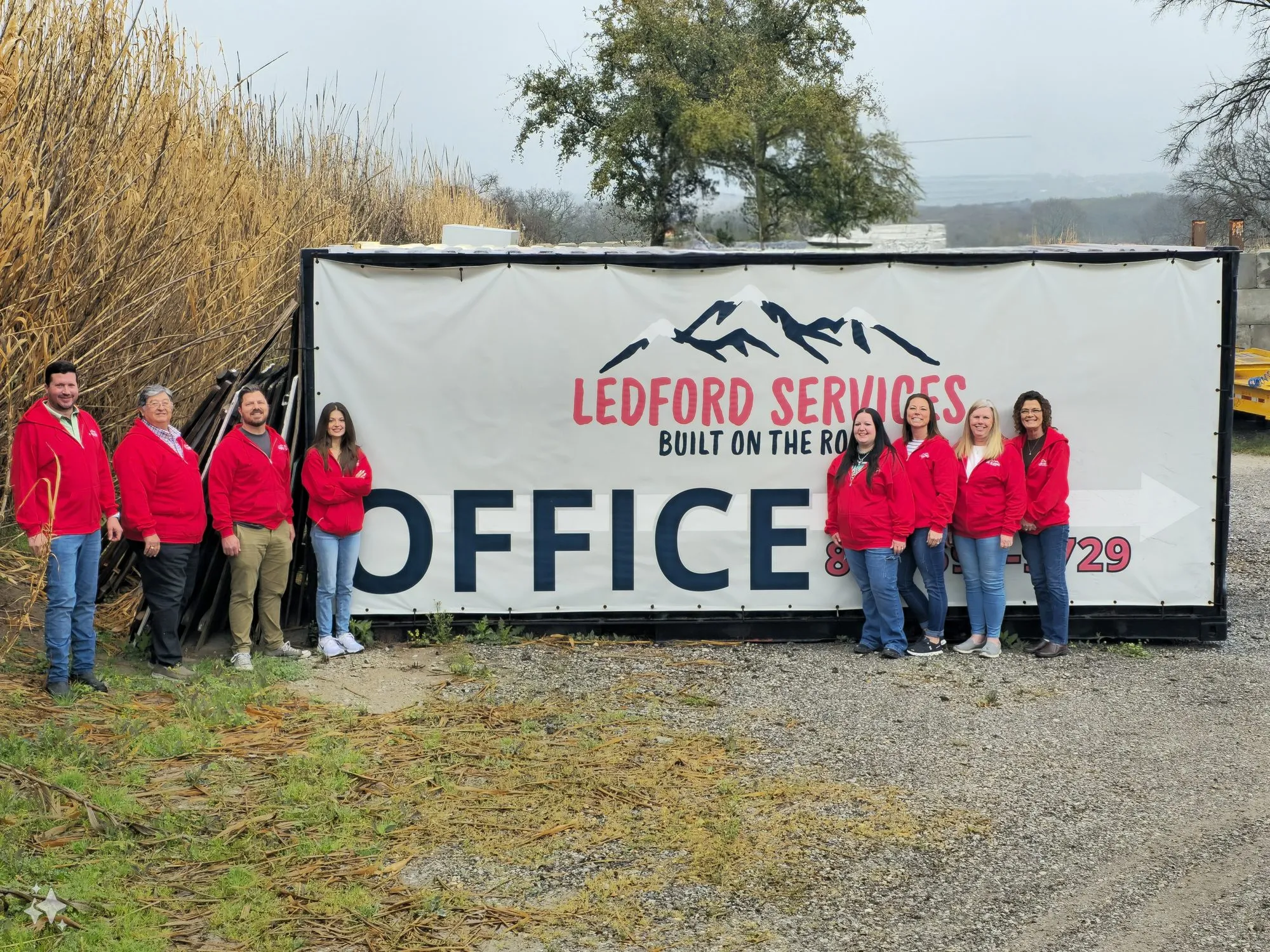 The Ledford Services office team in front of the company banner